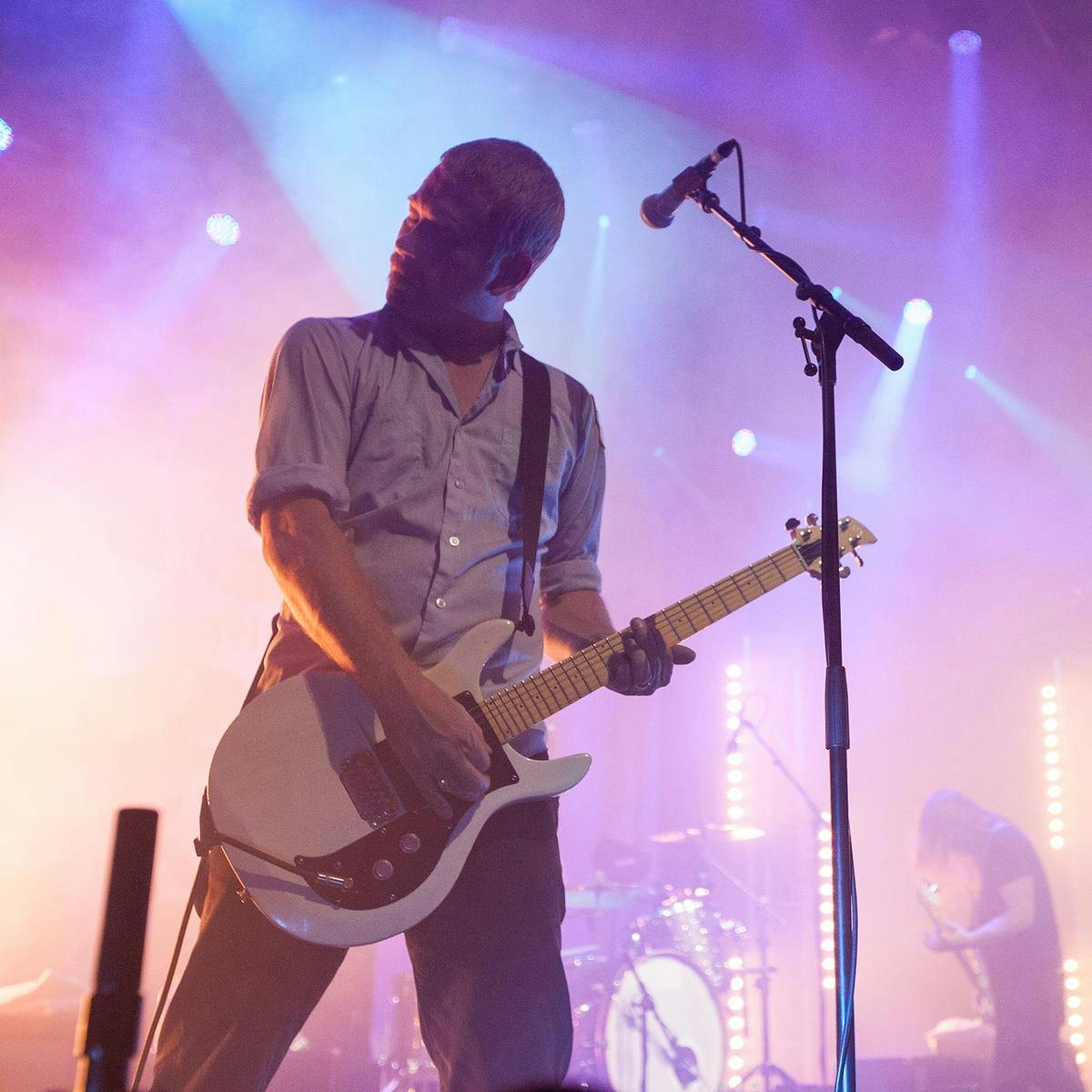 Three members of 'The Bronx' perform on stage, the main focus the guitarist.