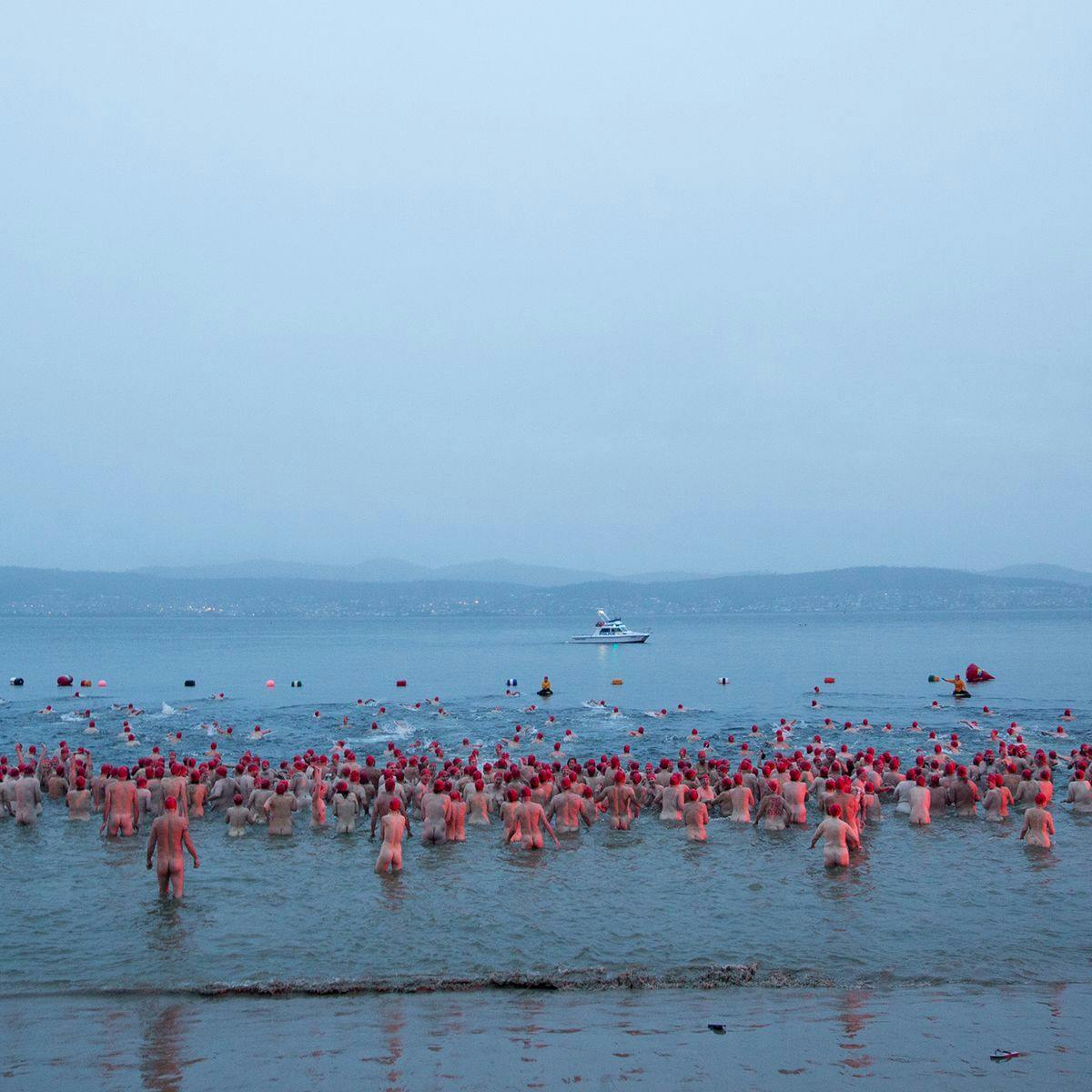 Hundreds of people walk and swim in the ocean, as part of 'Nude Solstice Swim'.