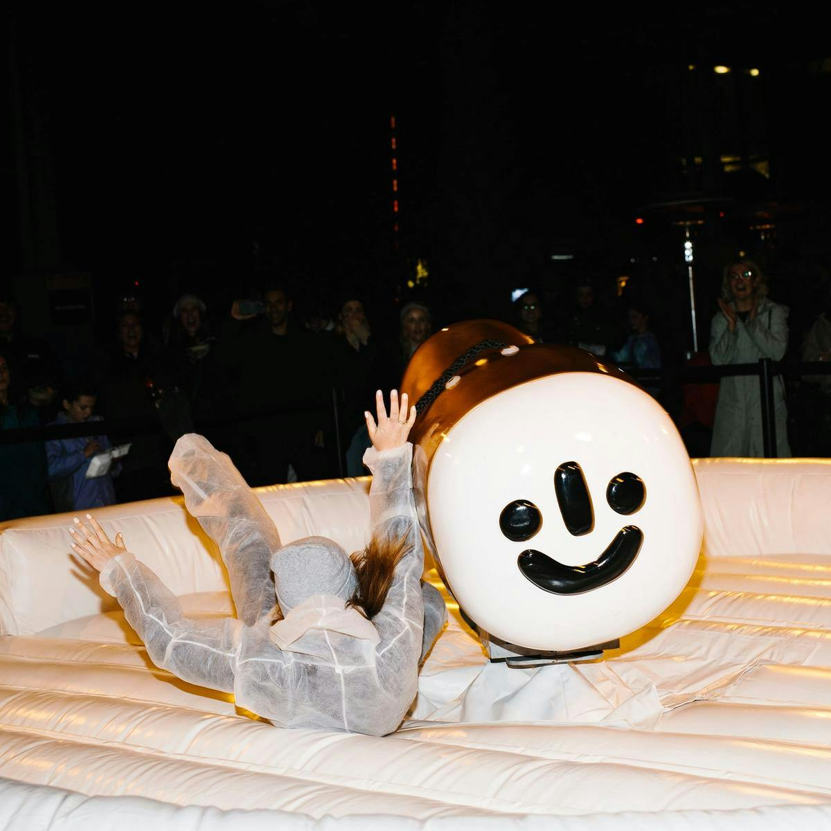 A person mid-air falls to the floor of an inflated ring, having just been bucked from a mechanical bull ride.