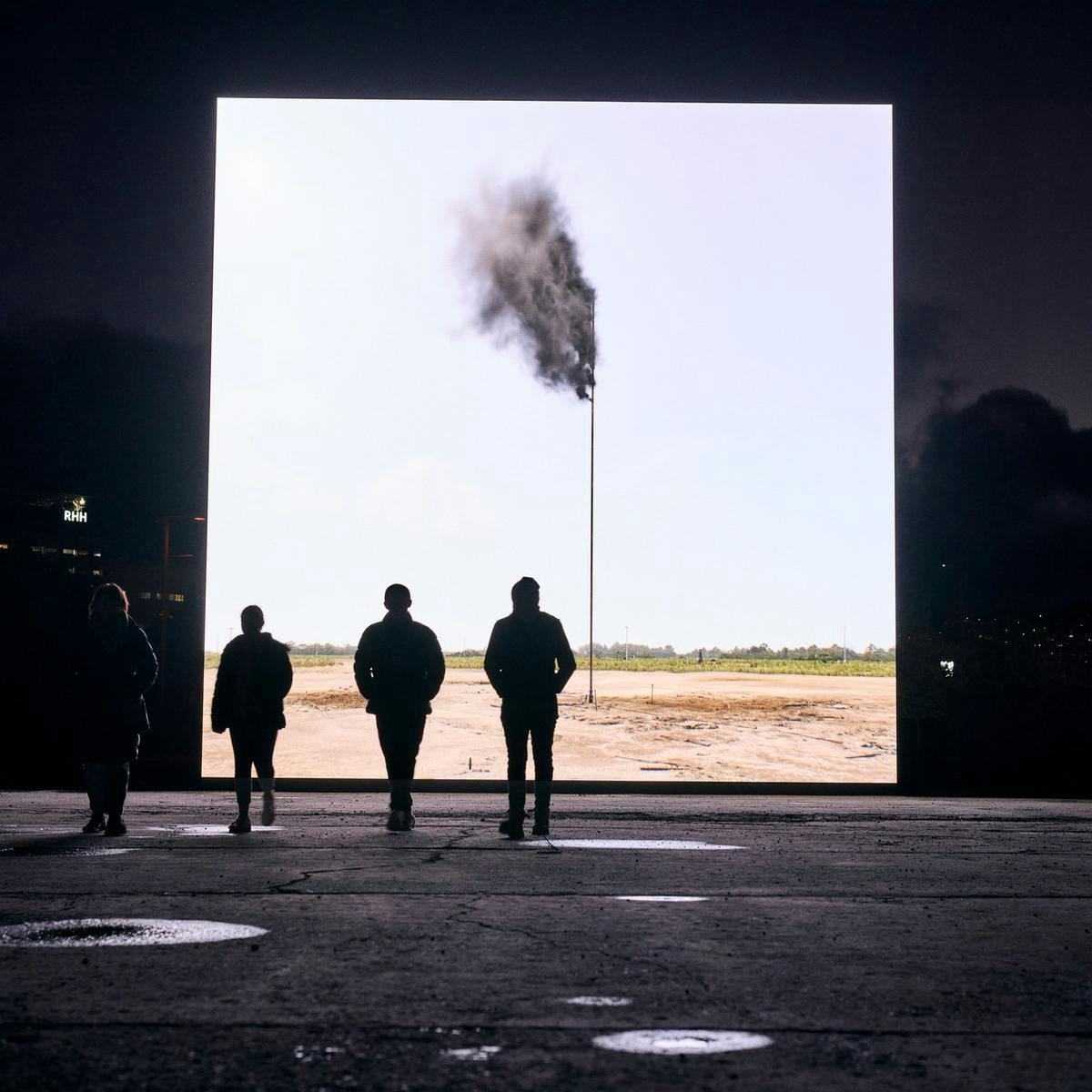 4 people watching a flag from black smoke on a big projection