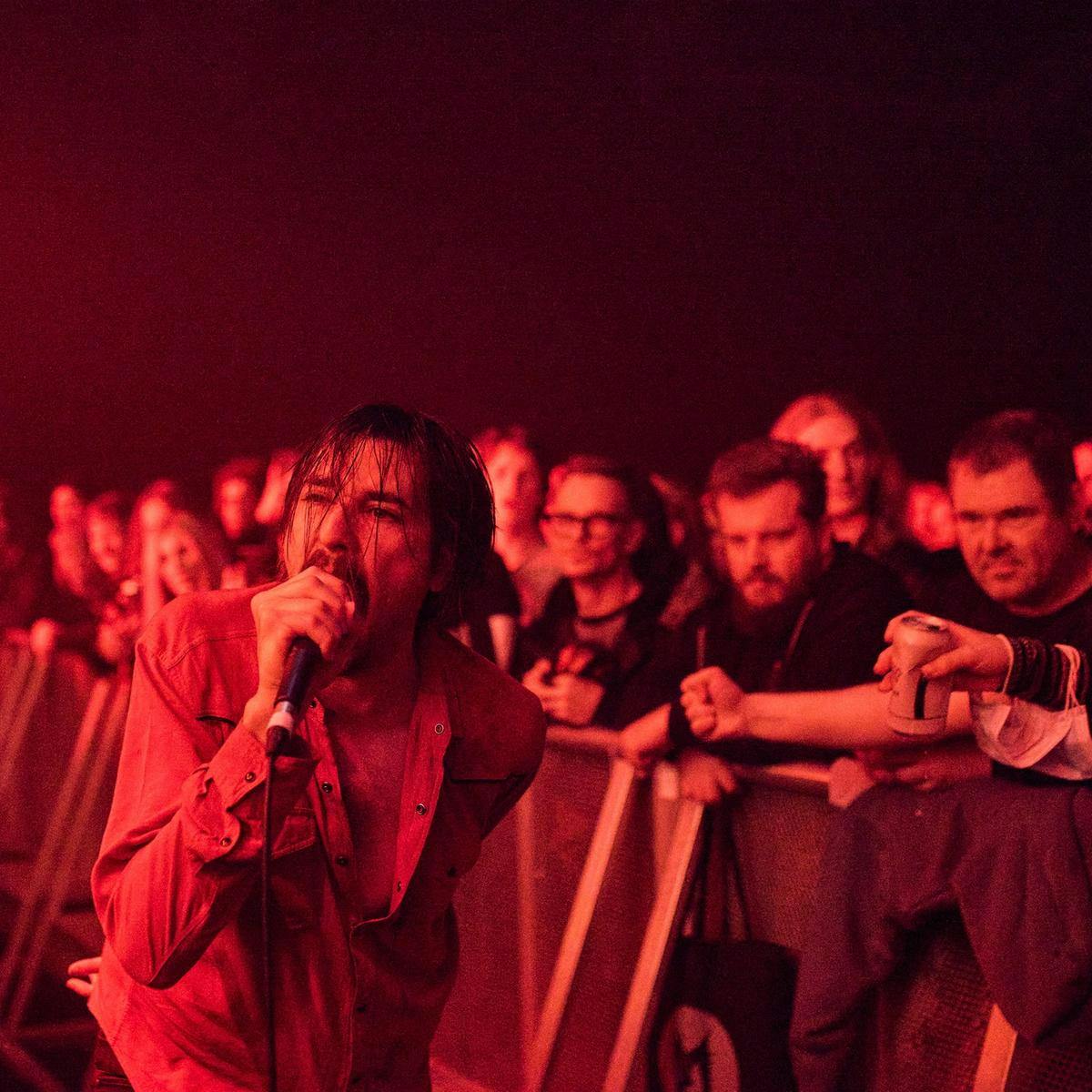 A member of 'Black Sheep Wall' is down at crowd level performing with a microphone, separated by a metal barrier, are several people in the crowd.