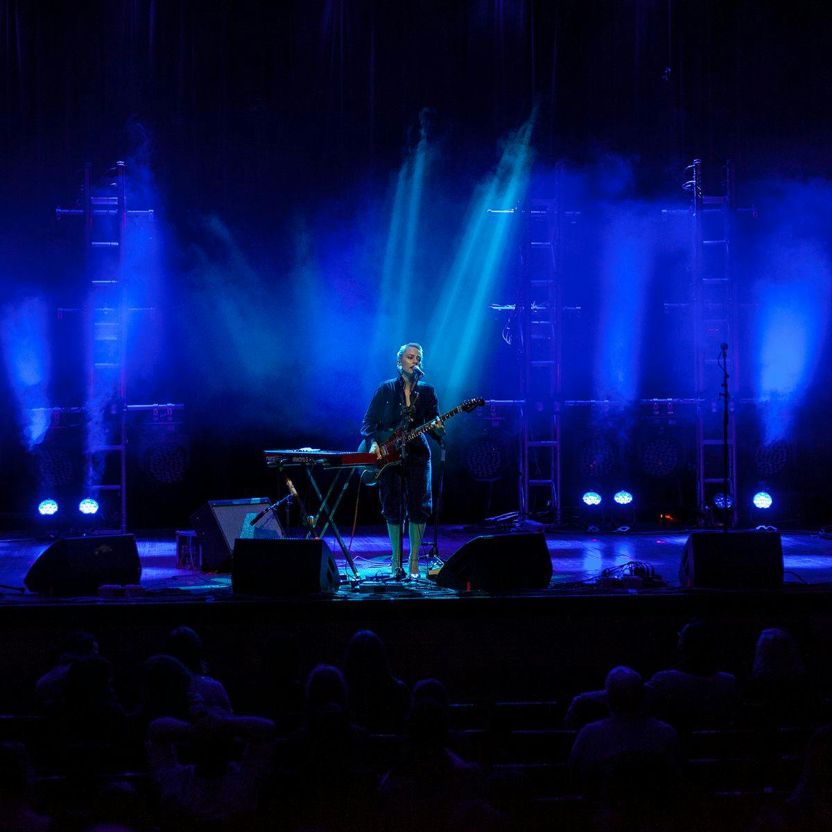 'Olympia' performs on stage, blue lights up the background.