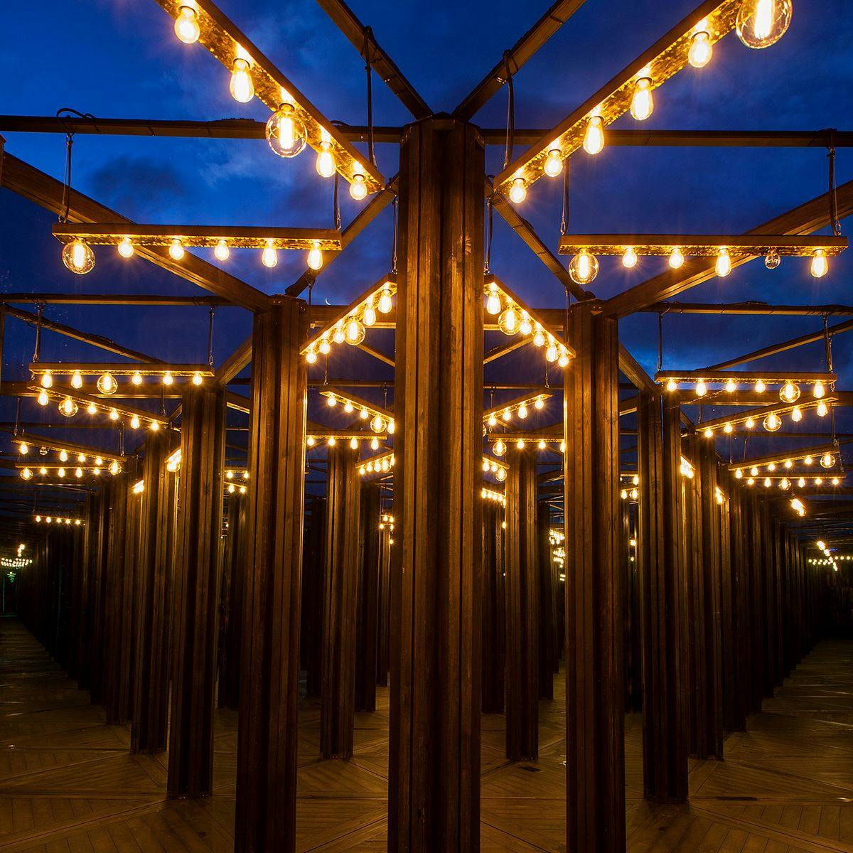 A room of mirrors, wooden floors and light bulbs overhead.