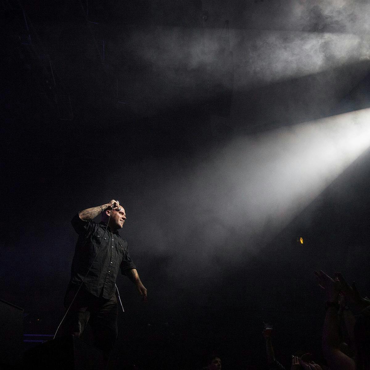 A person performs on-stage, two foggy beams of white light the scene.