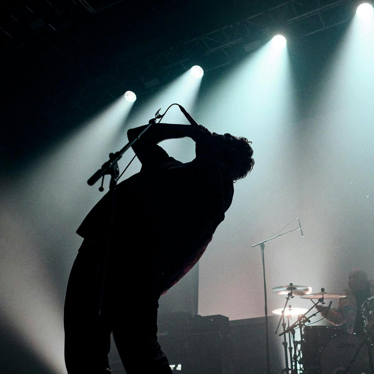 A silhouetted member of King Yosef performs on stage.