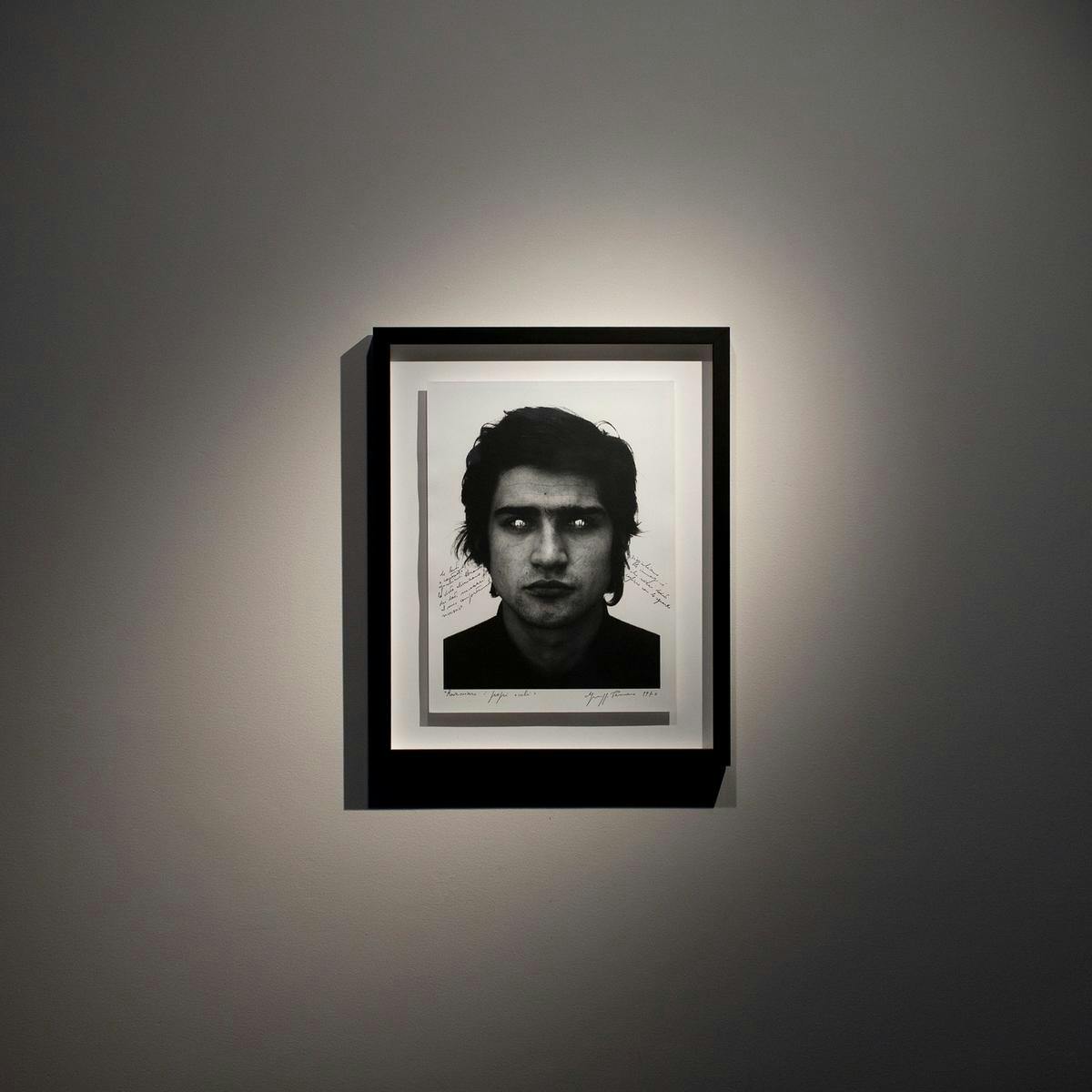 A portrait shot of a man, framed on a wall.