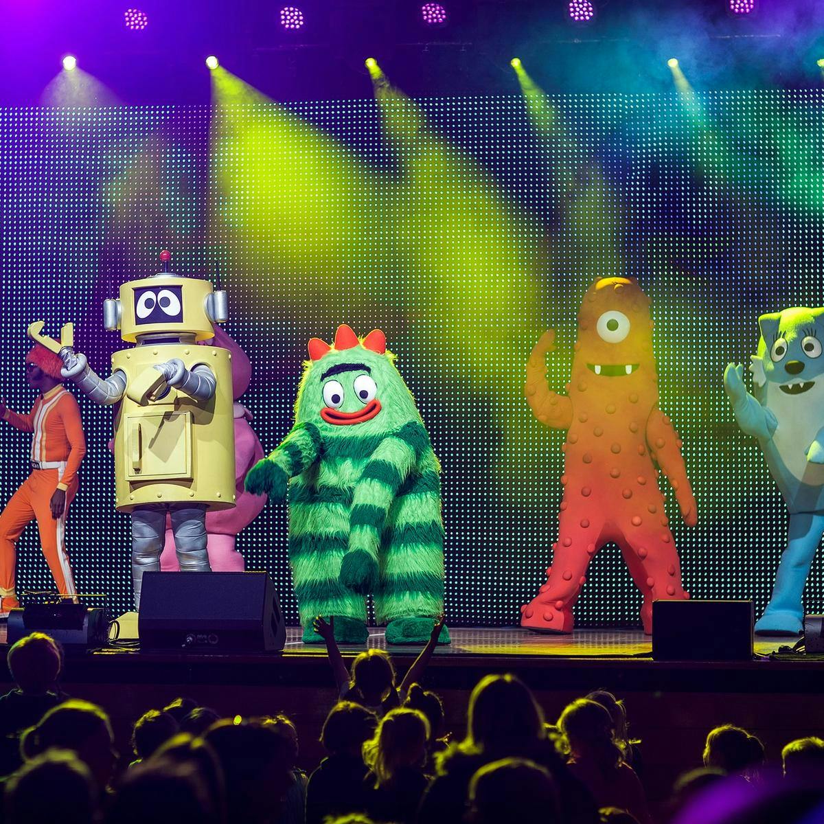 Five members of 'Yo Gabba Gabba' perform to a large audience of children.