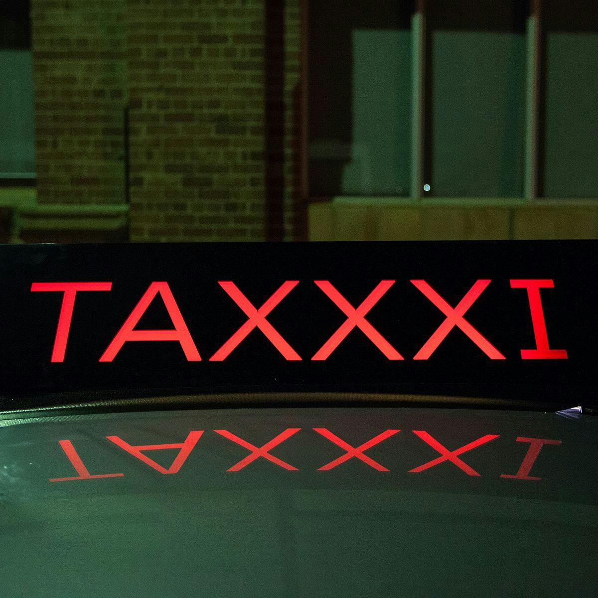 A car-topper sign that reads 'Taxxxi'.