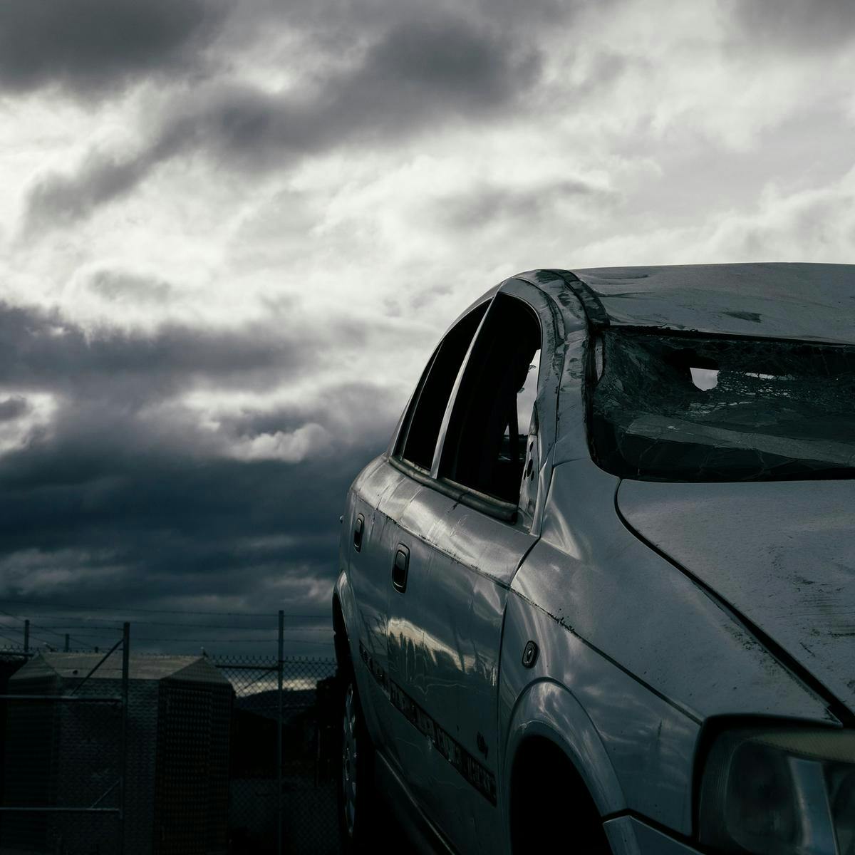 A broken and partially crushed car, with several spots of damage and smashed windows.