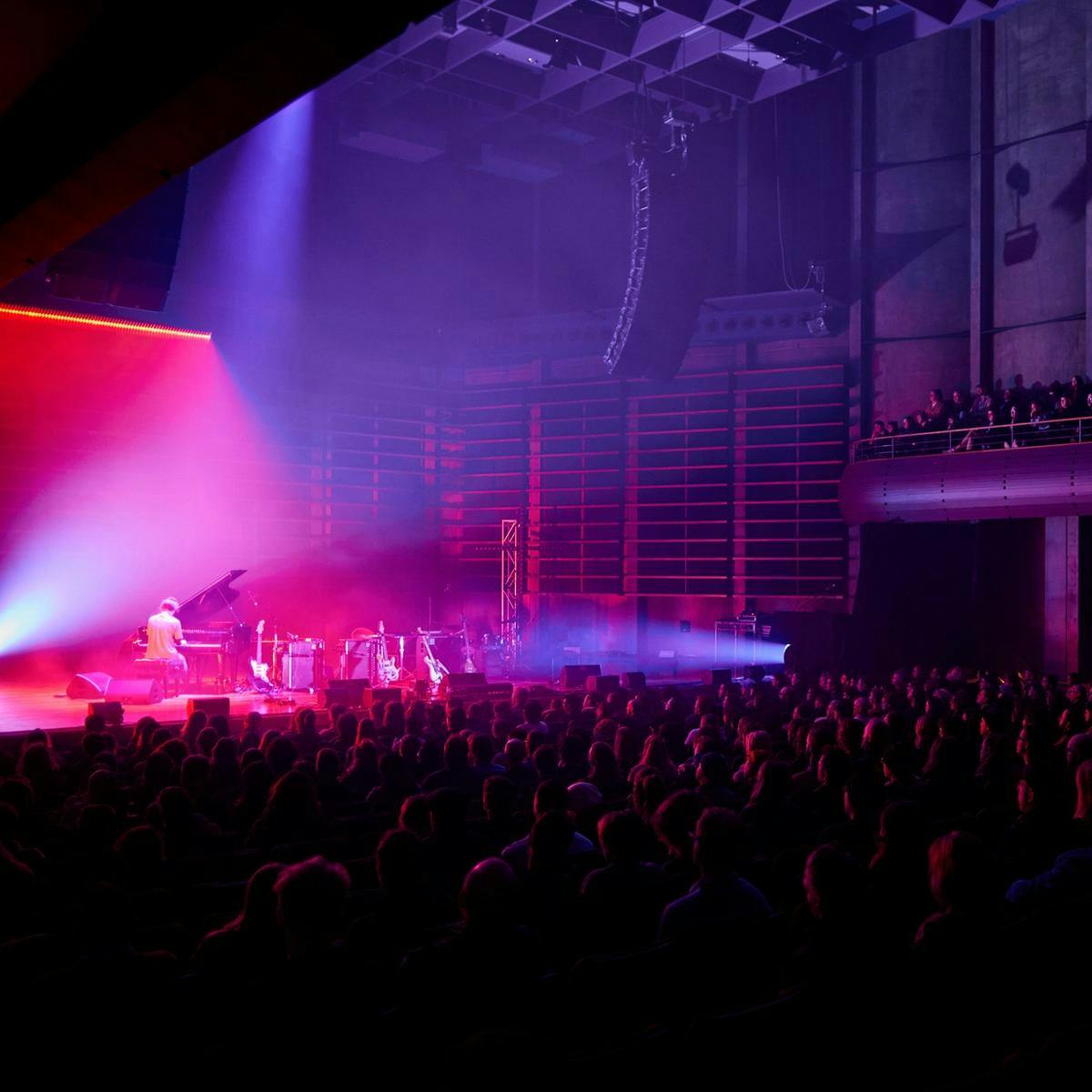 A large seated crowd watch someone play piano on stage, at the Federation Concert Hall.