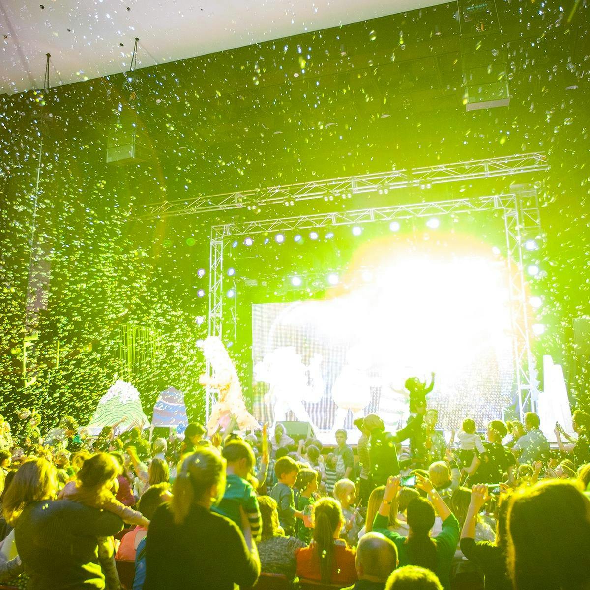 Bright yellow light and hundreds of bubbles fall onto a crowd of many children as they watch 'Yo Gabba Gabba' perform.